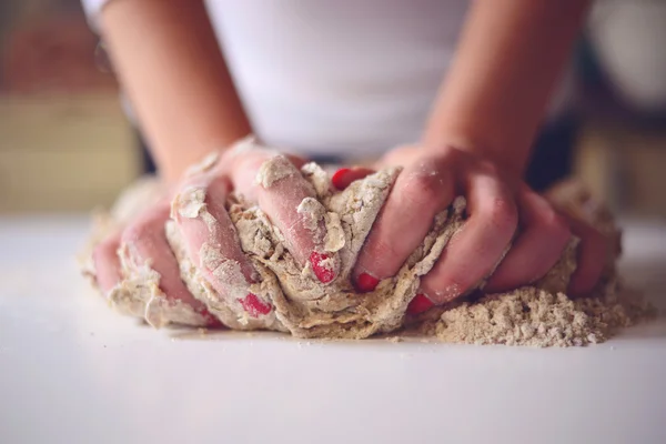 Les mains de la femme pétrissent la pâte sur une table — Photo