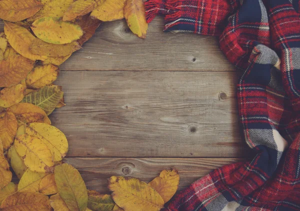 Flat lay view of autumn leaves and tartan textured scarf on wood — Stock Photo, Image