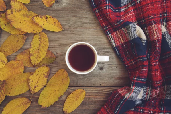 Flat lay view of autumn leaves and tartan textured scarf on wood — Φωτογραφία Αρχείου