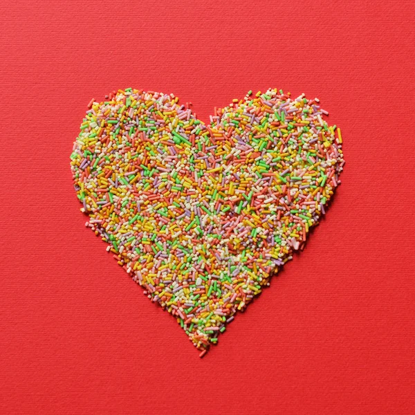 Forma de corazón hecha de chispas de caramelo multicolores - Mínimos modernos —  Fotos de Stock