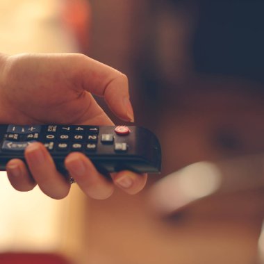 Uzaktan kumanda tutan eller kadın