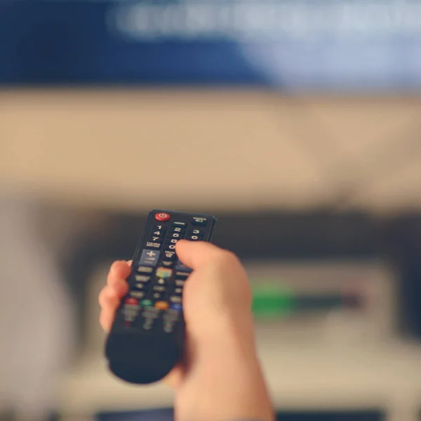 Mão segurando controlador de tv remoto para televison — Fotografia de Stock