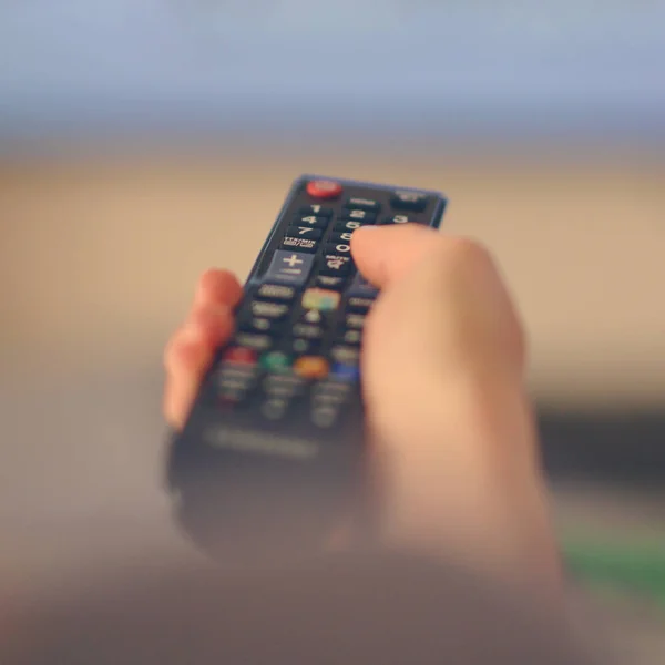 Hand holding remote tv controller towards televison — Stock Photo, Image