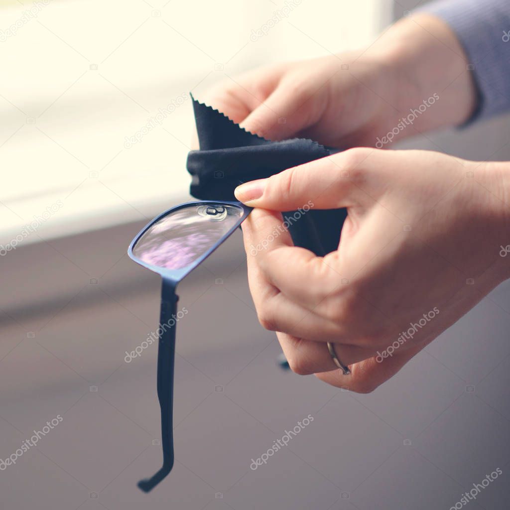 Woman cleaning reading glasses with cloth