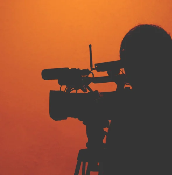 Silhueta de cameraman contra fundo laranja claro — Fotografia de Stock