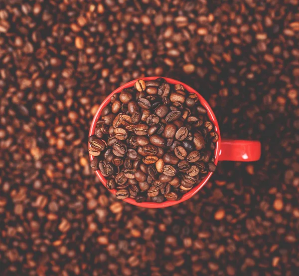 Kırmızı fincan kahve kahve çekirdekleri zemin üzerine — Stok fotoğraf
