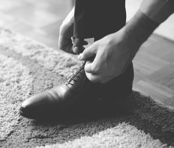 Man koppelverkoop de veters op zwarte schoenen - zwart-wit foto — Stockfoto