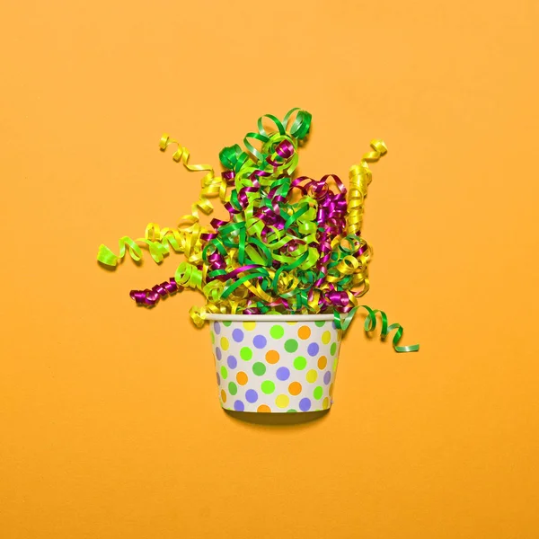 Veelkleurige confetti explosie van cup op gele achtergrond - — Stockfoto