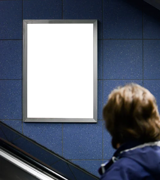 Hombre mirando la cartelera en blanco mientras que sube en escalera mecánica —  Fotos de Stock