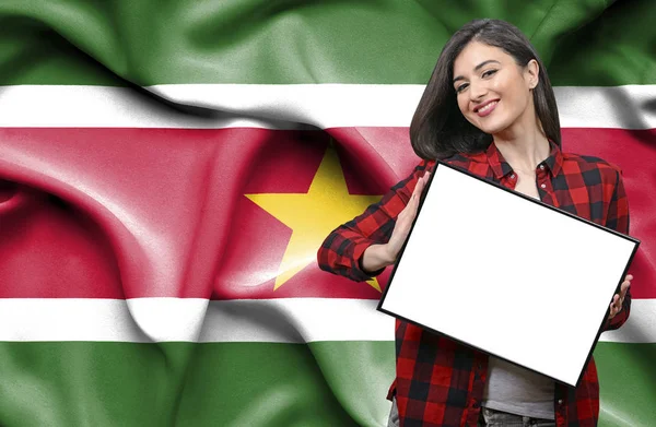 スリナムの国旗に対して空白のボードを持った女性 — ストック写真
