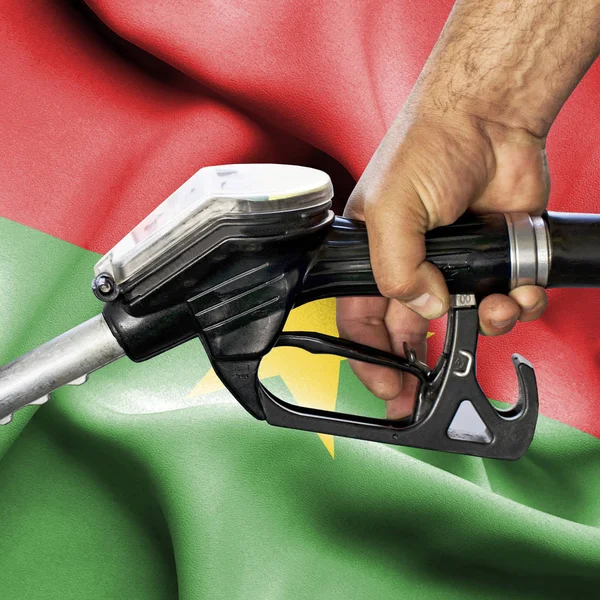 Conceito de consumo de gasolina - Mangueira de retenção de mão contra bandeira de — Fotografia de Stock