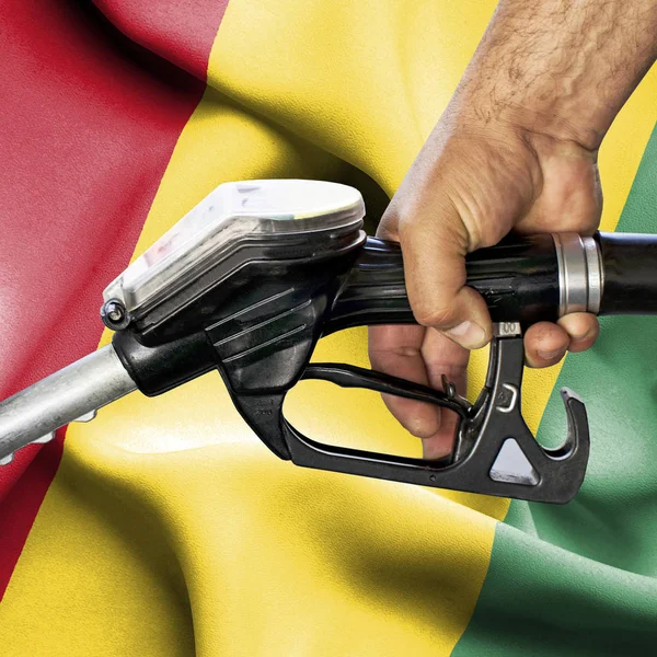 Gasoline consumption concept - Hand holding hose against flag of — Stock Photo, Image