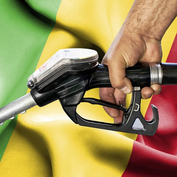 Gasoline consumption concept - Hand holding hose against flag of — Stock Photo, Image