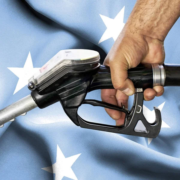 Концепція споживання бензину - Рука тримає шланг проти прапора — стокове фото
