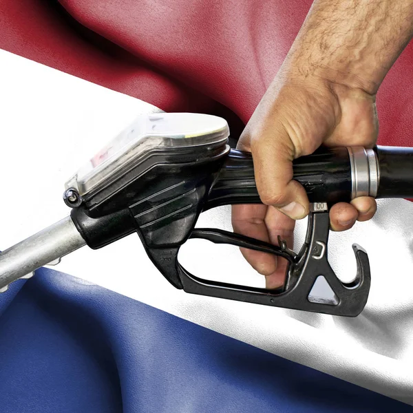 Conceito de consumo de gasolina - Mangueira de retenção de mão contra bandeira de — Fotografia de Stock