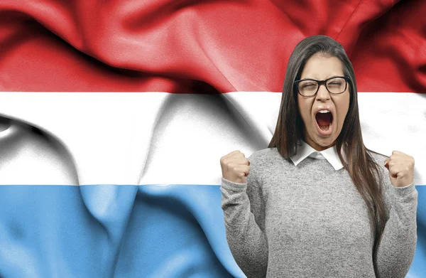 Mujer extática holidng puños y gritando contra la bandera de Luxem —  Fotos de Stock