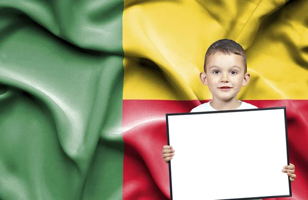 Bonito menino pequeno segurando sinal emtpy na frente da bandeira de Benin — Fotografia de Stock