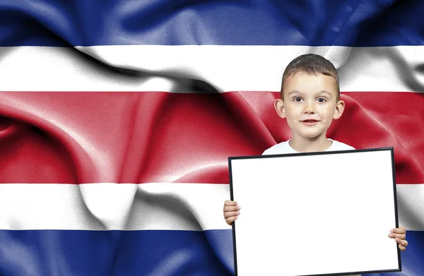 Lindo niño pequeño sosteniendo letrero de emtpy frente a la bandera de Costa Rica — Foto de Stock