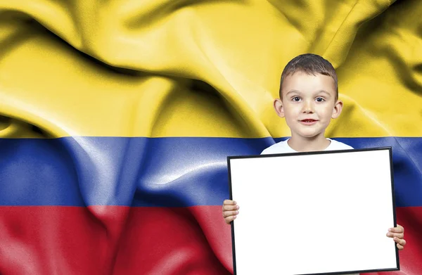 Cute small boy holding emtpy sign in front of flag of Columbia — Stock Photo, Image