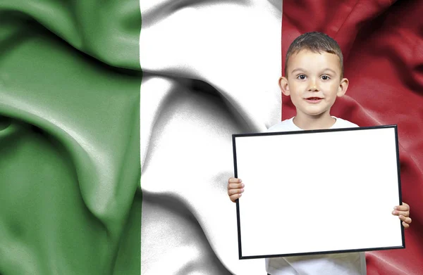 Lindo niño pequeño sosteniendo el cartel de emtpy delante de la bandera de Italia — Foto de Stock