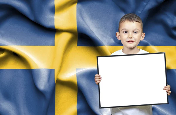 Sød lille dreng holder emtpy tegn foran flag Sverige - Stock-foto