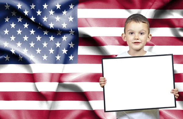 Lindo pequeño niño sosteniendo el cartel de emtpy delante de la bandera de United Sta —  Fotos de Stock