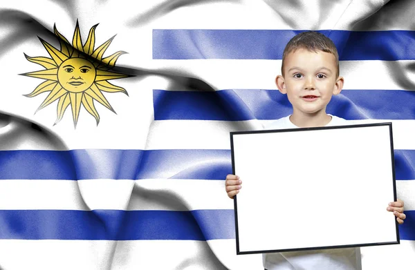 Roztomilý malý chlapec s emtpy značka před vlajka Uruguaye — Stock fotografie