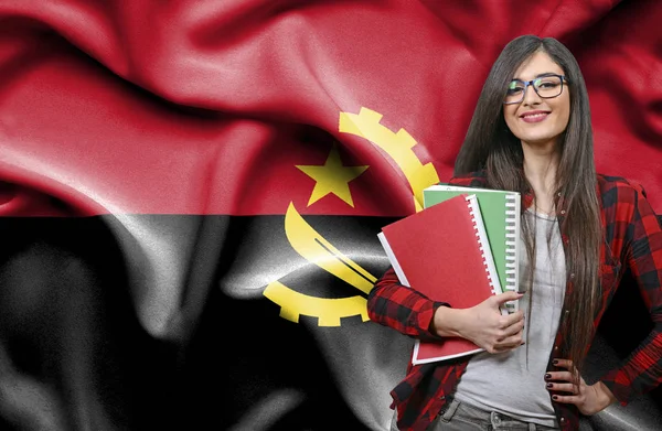 Szczęśliwy kobiet student holdimg książek przeciwko Flaga narodowa Ango — Zdjęcie stockowe