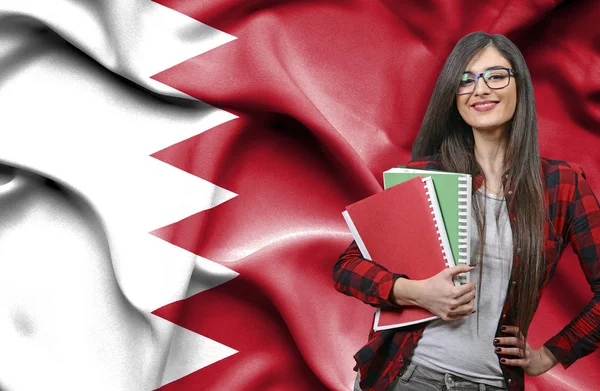 Glad kvinnlig student holdimg böcker mot flagga Bahr — Stockfoto
