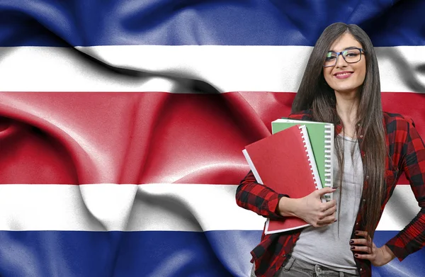 Happy female student holdimg books against national flag of Thai — Stock Photo, Image