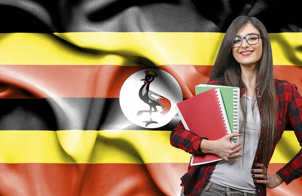 Szczęśliwy kobiet student holdimg książek przeciwko Flaga narodowa Ugan — Zdjęcie stockowe