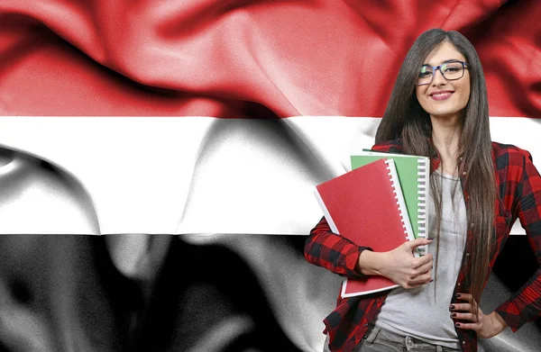 Szczęśliwy kobiet student holdimg książek przeciwko Flaga narodowa Yeme — Zdjęcie stockowe