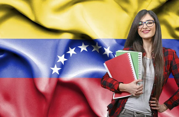 Happy female student holdimg books against national flag of Vene — Stock Photo, Image