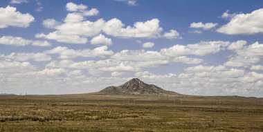 Pitoresk bozkır manzara Dağı, mavi gökyüzü bulutlu bir arka plan üzerinde seyrek bitki örtüsü ile bozkırlarında        