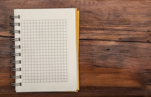 Página de caderno em branco está no topo da mesa de mesa de escritório de madeira — Fotografia de Stock