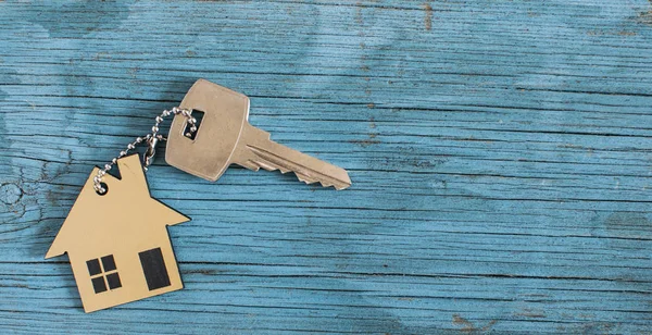 Символ дома с серебряным ключом на винтажном деревянном фоне — стоковое фото