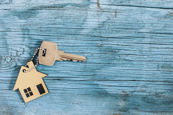 Símbolo de la casa con llave de plata sobre fondo de madera vintage — Foto de Stock