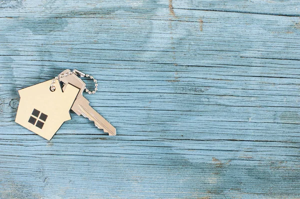 Symbolem domu z srebrny klucz na drewniane tło — Zdjęcie stockowe