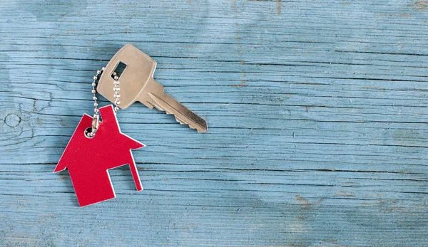 Symbol des Hauses mit silbernem Schlüssel auf Holzgrund — Stockfoto