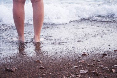 Gün batımında kumsalda güzel kadın bacakları