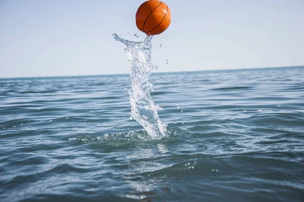 Orange water polo ball on blue water background — Stock Photo, Image