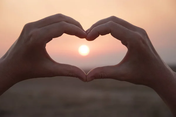 Hand shaped heart against a beautiful sunset — Stock Photo, Image