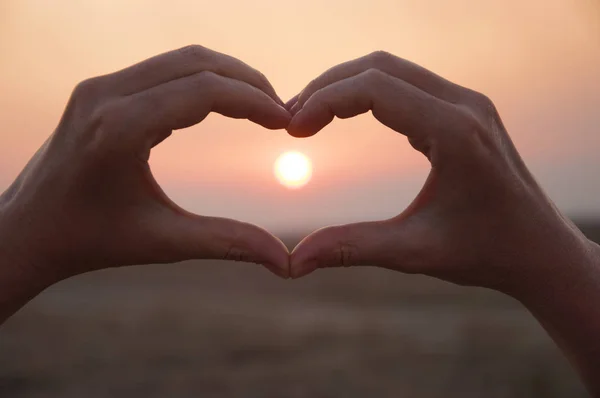 Hand shaped heart against a beautiful sunset — Stock Photo, Image