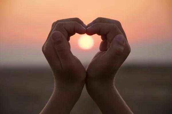 Hand shaped heart against a beautiful sunset — Stock Photo, Image