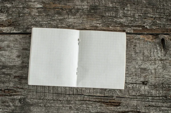 Notebook in een kooi op een houten achtergrond — Stockfoto
