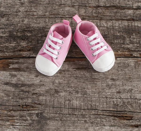 木製の背景に赤ちゃんの靴 — ストック写真