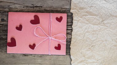 pembe zarf ve Sevgililer günü için ahşap masa üzerinde küçük kalp