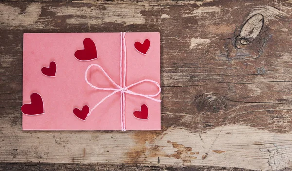 Червоні серця і рожевий конверт на дерев'яному фоні — стокове фото