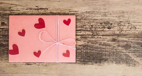 Rode harten en roze envelop op houten achtergrond — Stockfoto