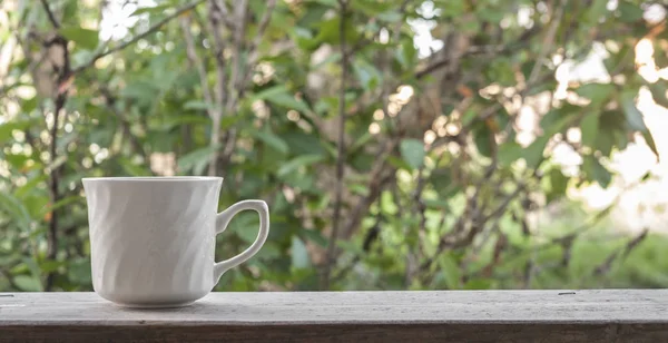 Witte cup op houten tafel buiten — Stockfoto